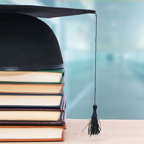 Graduation Cap And Books Stacked At School