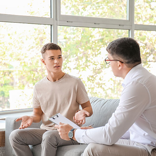 Psychologist Working With Teenage Boy In Office
