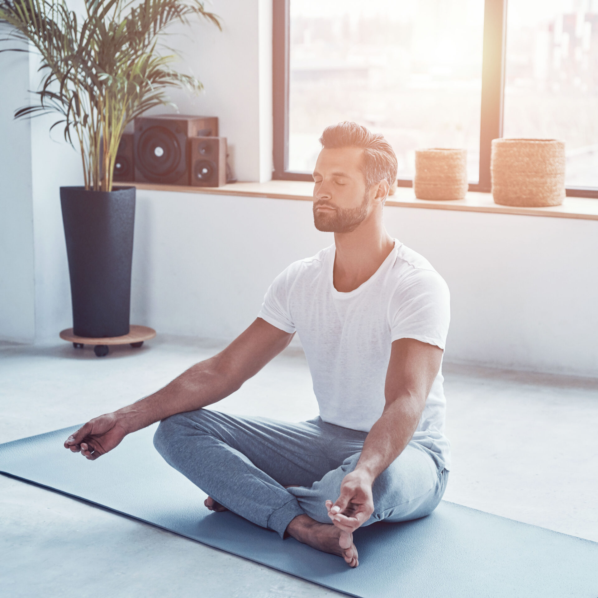 Totally Relaxed Young Man Doing Yoga While Sitting In Lotus Position At Home
